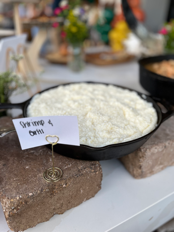 Shrimp and grits served in cast-iron skillets styled for a luxury outdoor birthday party.