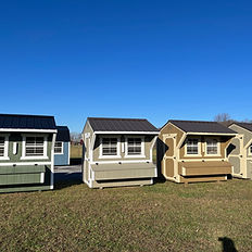 Row of colorful wooden chicken coops on grass under clear blue sky.