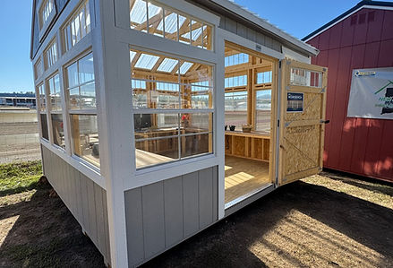 Modern gray and white greenhouse building with clear windows under blue sky.