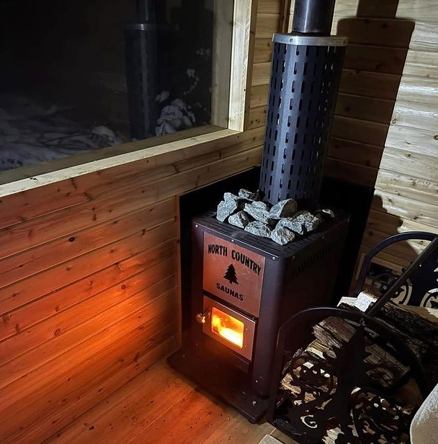 Wood-burning HARVIA LEGEND sauna stove with glowing embers and rocks atop.