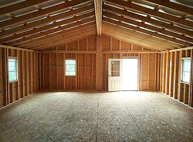 Interior of new wooden building construction with exposed framing, rafters, and floor.