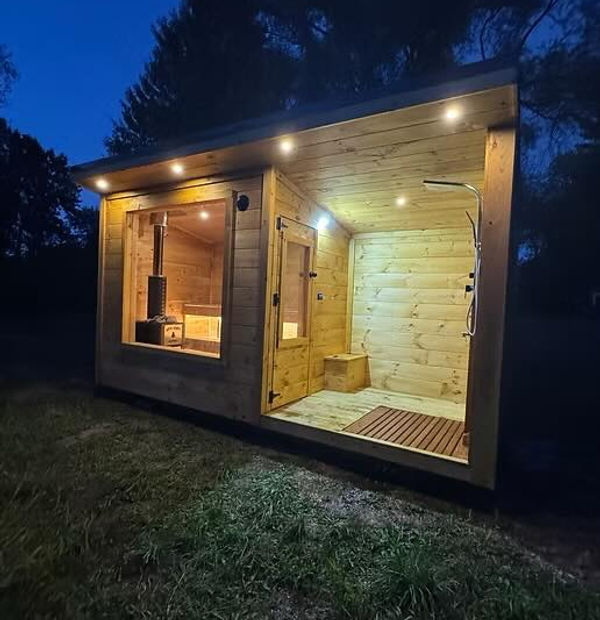 Modern wooden outdoor sauna building illuminated at night under dark sky.