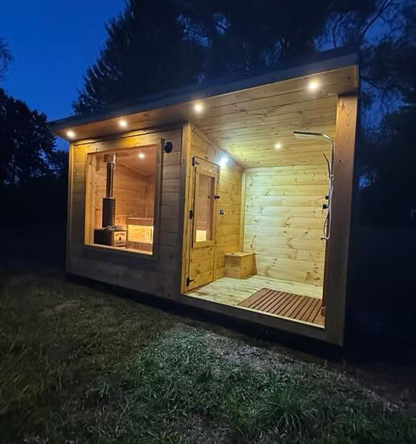 Outdoor wooden sauna building glowing at night, interior with wood stove.