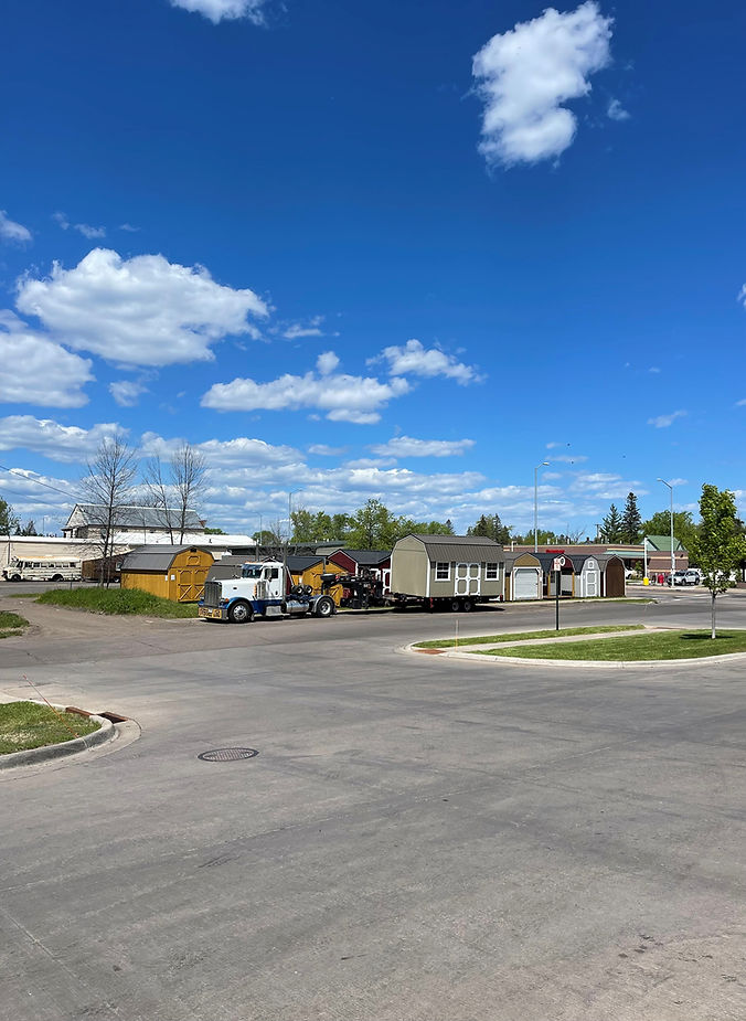 Truck transporting a modular building on a paved road under blue sky.