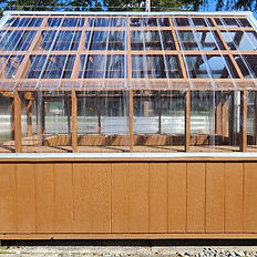 Compact brown wooden base Greenhouses with clear plastic roof panels.