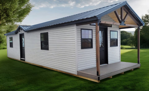 White modular tiny house with blue metal roof and front porch.