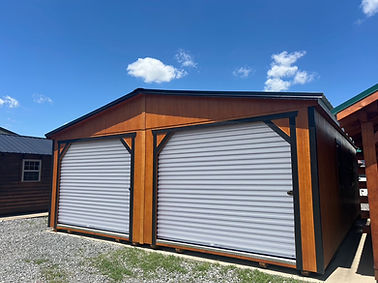 Double-bay wooden garage, two gray roll-up doors, clear sky.