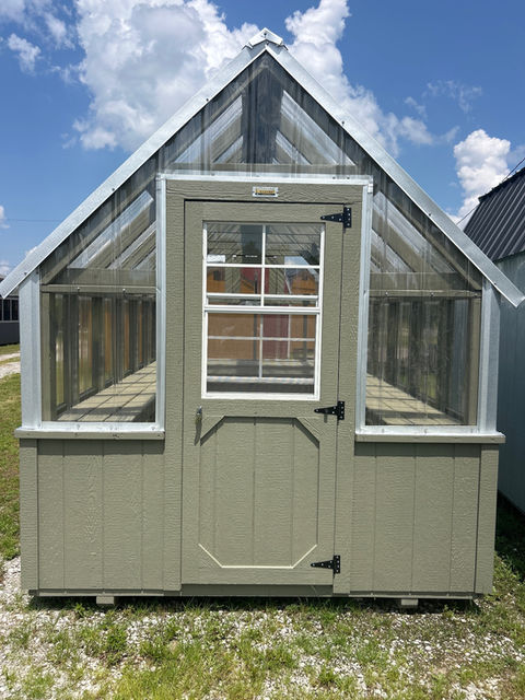 Outdoor light green wooden greenhouse with clear roof and glass panels.