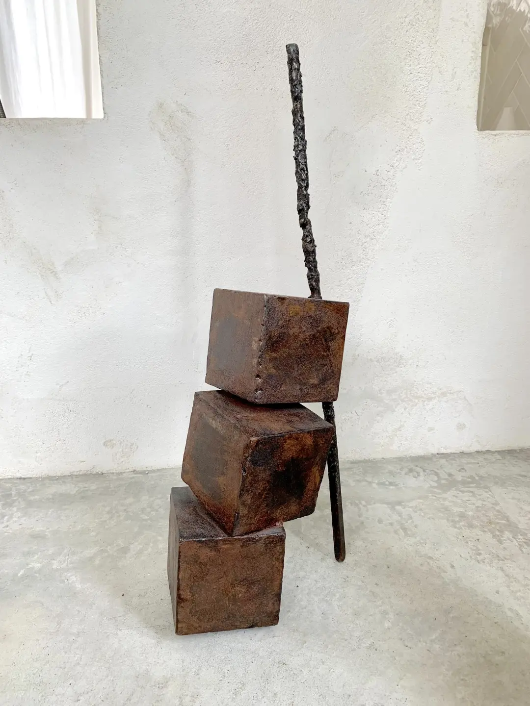 Sculpture de trois blocs de fer, équilibrés et suspendus, en Galerie Mourier.