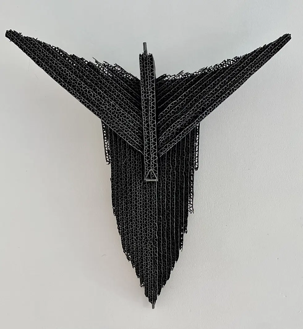 Sculpture noire en forme d'oiseau, sur fond blanc, détails de l'œuvre.