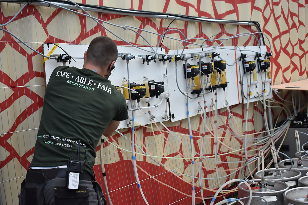 A man adjusting beer kegs behind a bar.