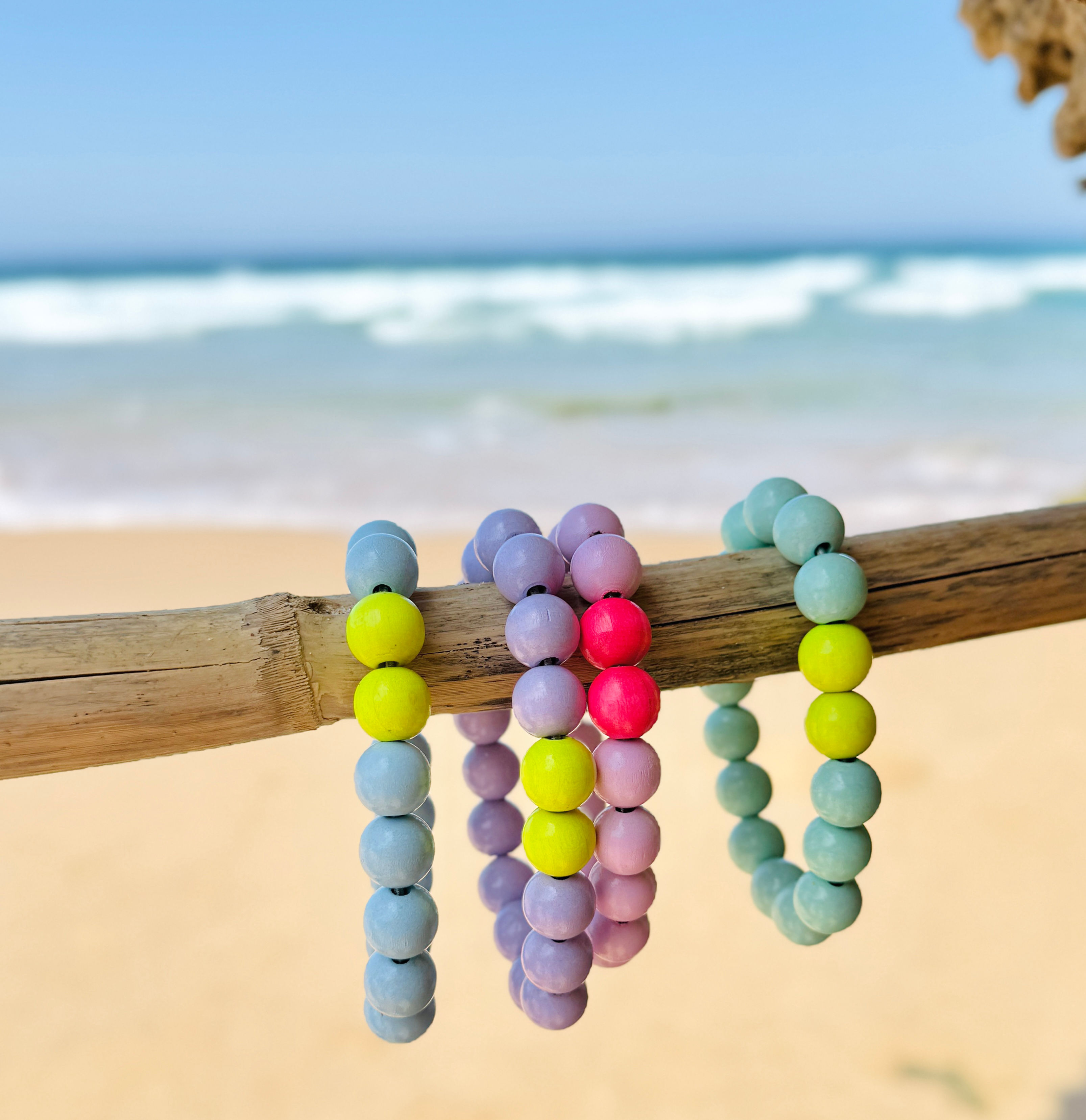 Armbänder aus Holzperlen auf einem Stock am Strand