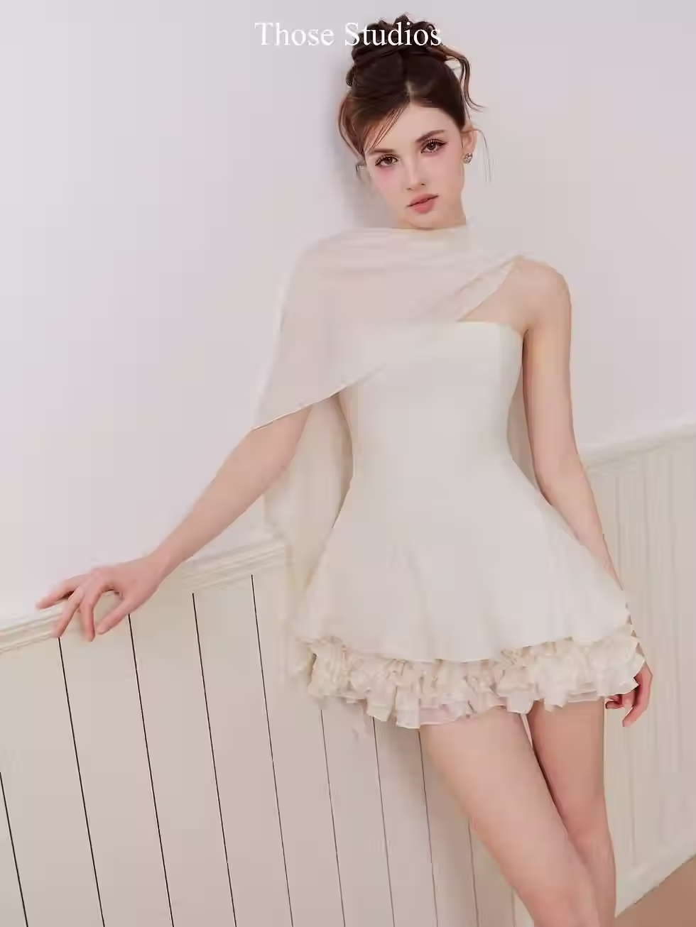 Elegant Natali Dress with cape and ruffled skirt, perfect for chic women's fashion, styled in soft cream tones.