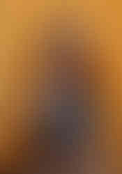 Joyful grandmother looking off to the side as she sits on a white stool against a yellow backdrop.