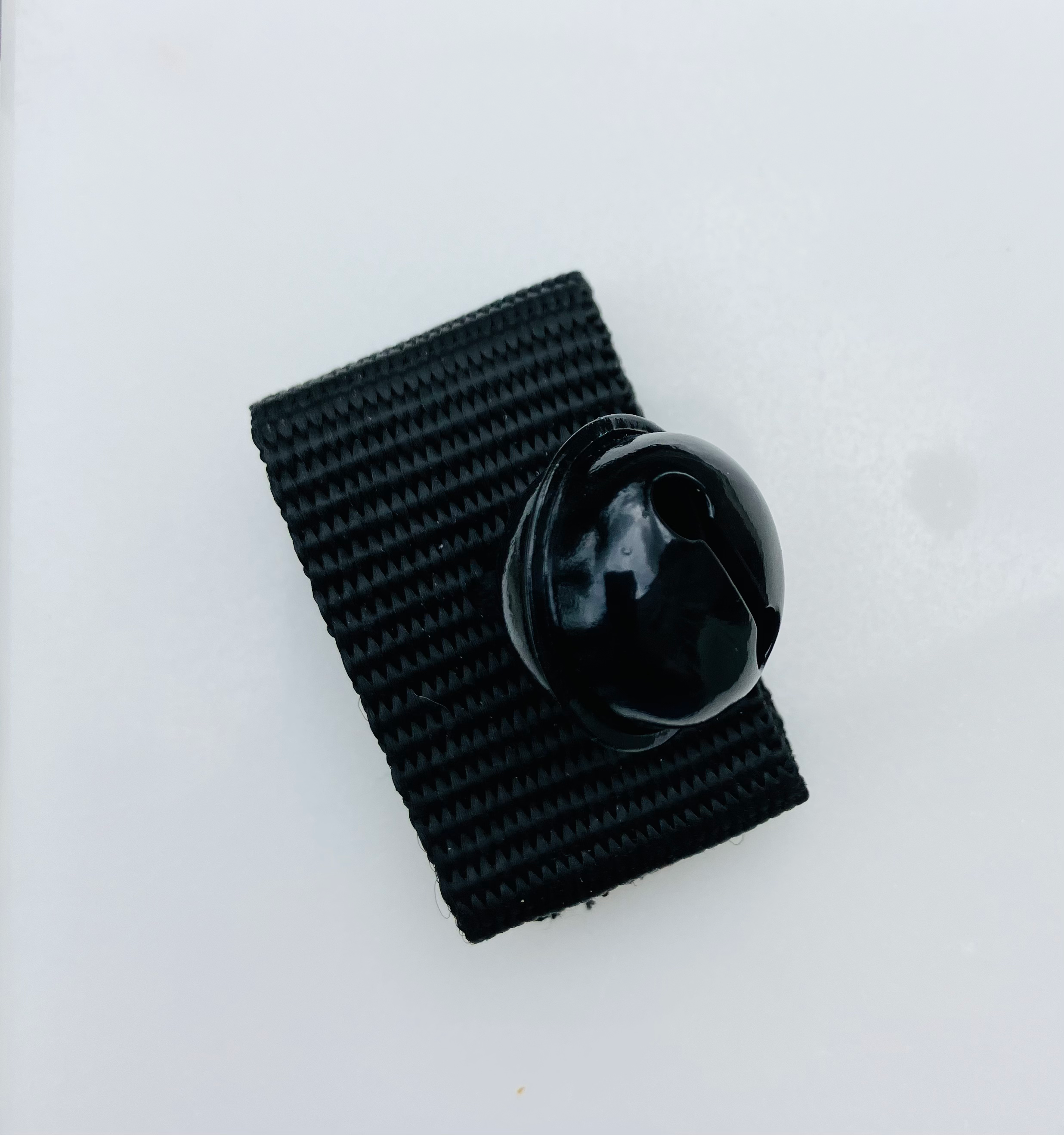 Zwart belletje voor aan de halsband met klittenbandsluiting, handgemaakt van stevig nylon.