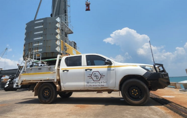 A white utility truck branded with "GD Contracting & Concrete" is parked on a dockside under a clear blue sky.
