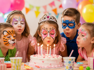 Animation maquillage enfant lors d’un anniversaire à domicile : plusieurs enfants maquillés soufflent les bougies autour du gâteau dans une ambiance joyeuse et festive.