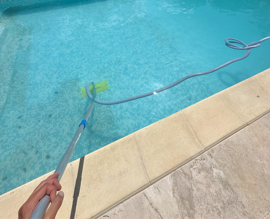 Entretien complet de piscine : nettoyage du fond et de la surface par un technicien avec balai aspirateur pour une eau cristalline.