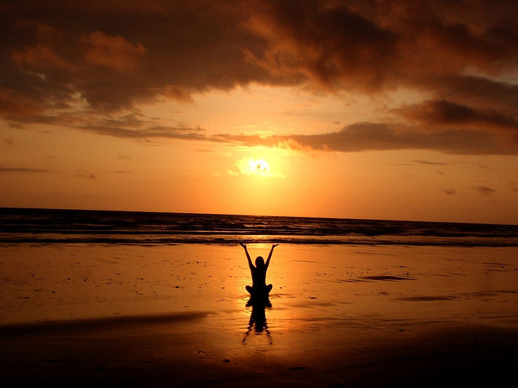 Beautiful sunset on the beach and meditated woman
