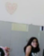 At Camp Waukeela a girl smiling in front of a mirror, beside a heart-shaped note on the wall saying, "Talk to yourself like someone you love."