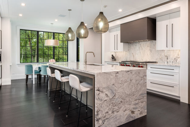 Scarsdale kitchen with a waterfall marble island, upholstered stools and statement pendant lights.
