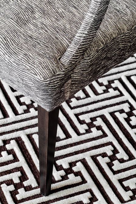 Close-up of textured grey chair upholstery above a graphic black-and-white area rug.