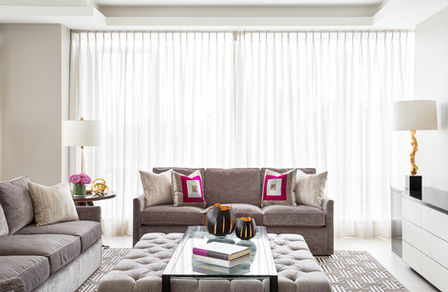 Contemporary living room with grey sofas, a tufted ottoman and colourful accent cushions.