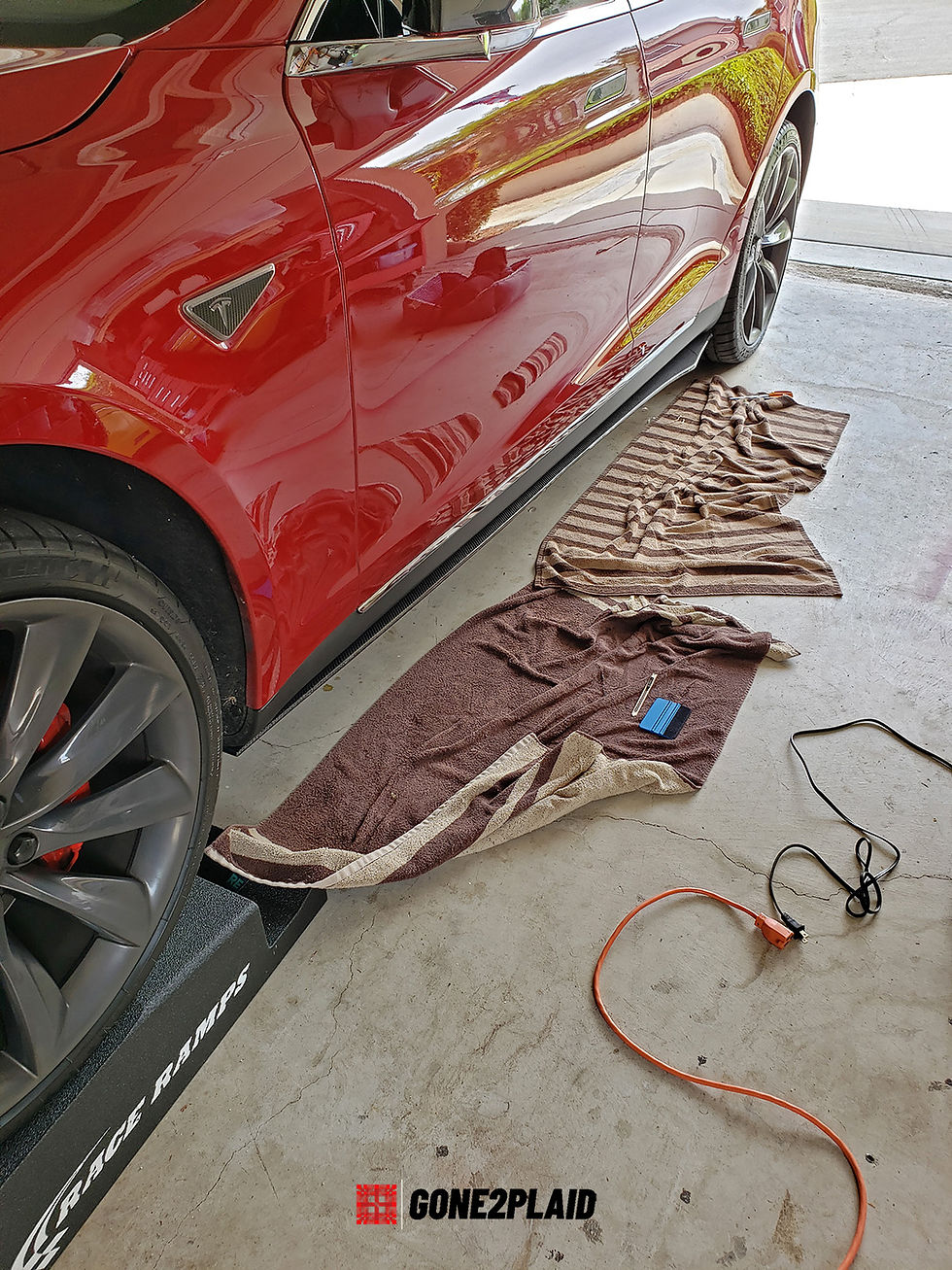 Red 2016 Tesla Model S P90DL with Ludicrous Mode. New custom carbon fiber skirts wrapping skirts in Paint Protective Film (PPF) after installation. Driver side.