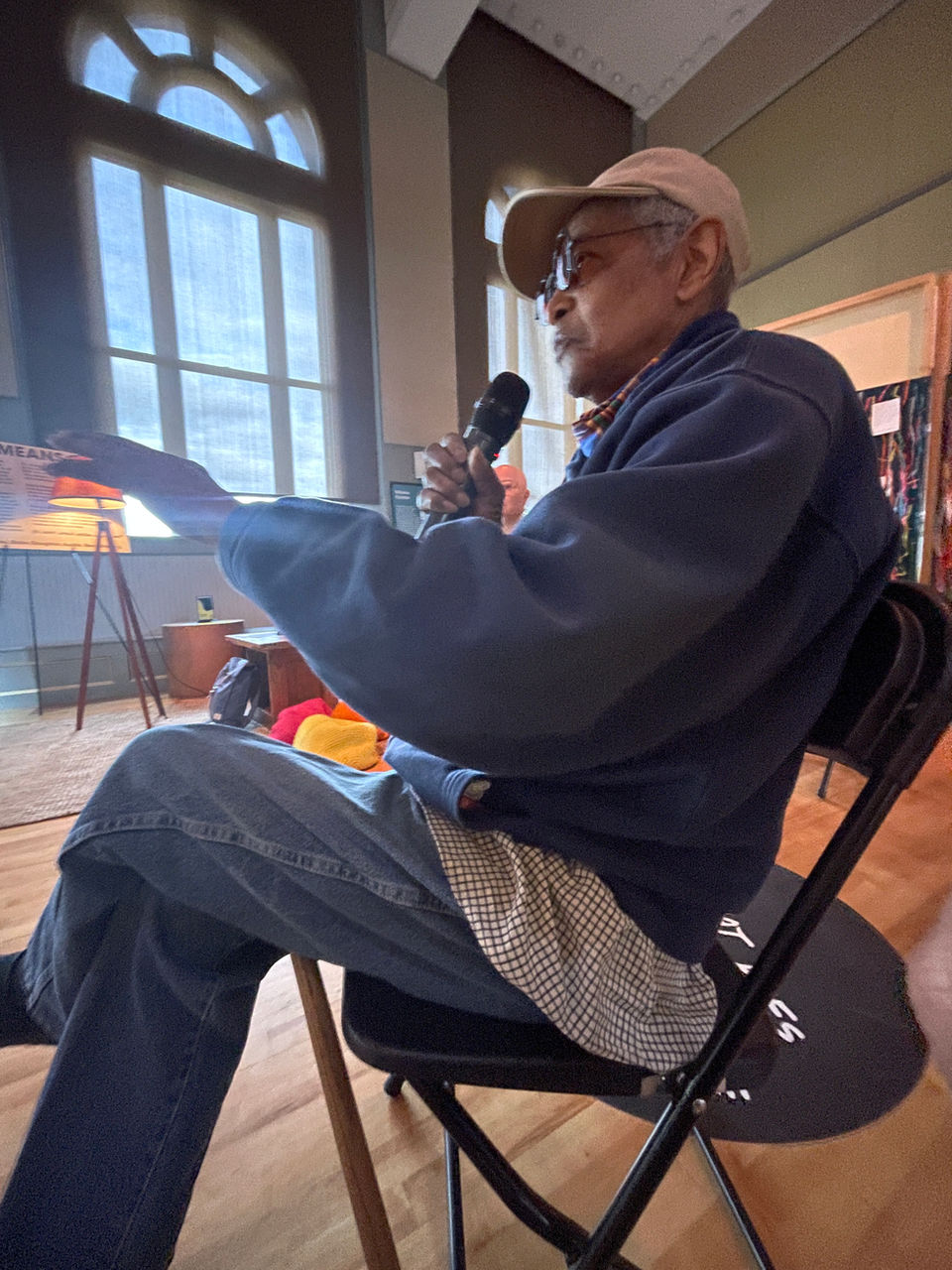 photo of artist Napoleon Jones-Henderson sitting in a chair with a mic, gesturing while talking