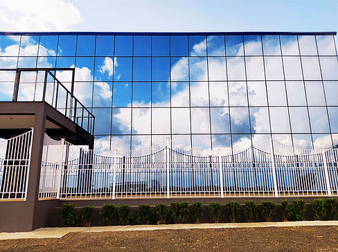 Fachada da empresa Aylag, toda espelhada com reflexo das nuvens.
