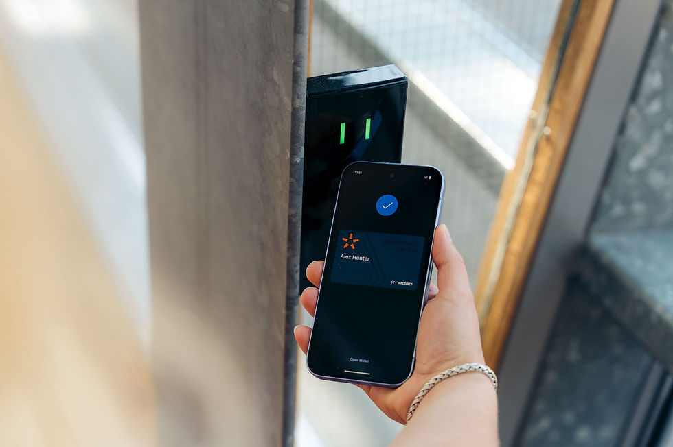 Smartphone utilisé comme badge mobile devant un lecteur mural pour ouvrir une porte d’accès sécurisée.