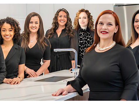 A group of professional women in coordinated black outfits, confidently gathering around a modern kitchen island.
