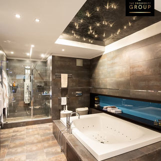 Luxurious and modern bathroom design featured in the Seller Guide from The Prosperity Group by eXp Realty, showcasing a sleek bathtub and a spacious glass-enclosed shower.