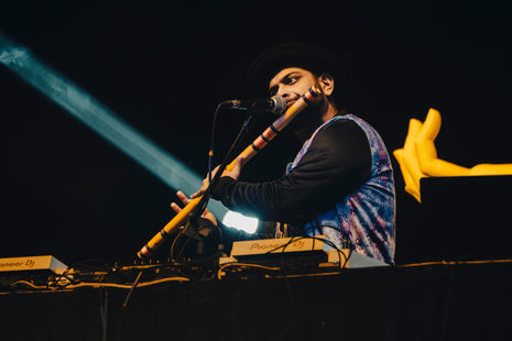 The combination of traditional instrument (flute) and modern equipment (DJ mixer) suggests a fusion or electronic music performance.