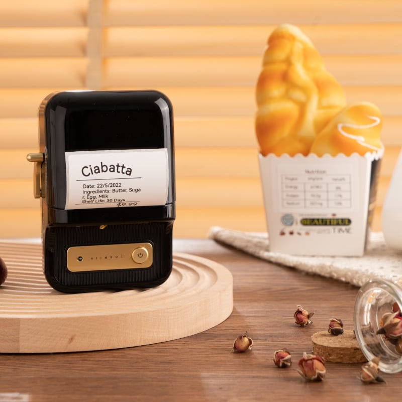 Niimbot B21 printing a label on a wooden kitchen counter with a pastry and coffee cup