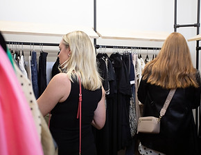Two women perusing maternity clothing on a shop rack