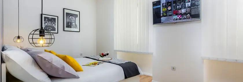 Cozy bedroom with bed, yellow pillows and TV inside Terra I apartment, Rijeka