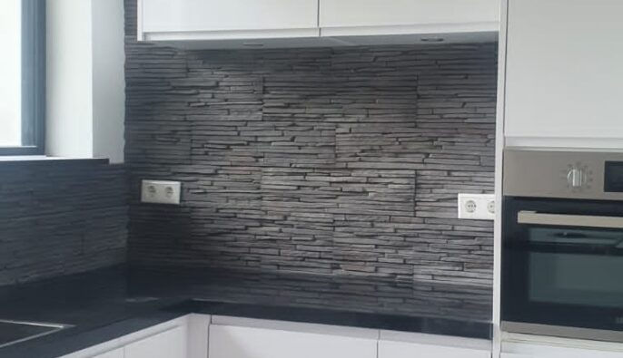 Keuken achterwand met een robuuste donkere steenstrip-afwerking en stopcontacten.