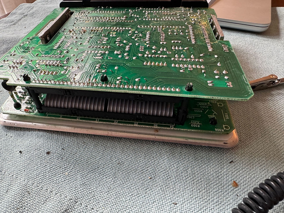 When the cover comes off, you have this circuit-board sandwich. The 2 plastic spacers on the ends are what you separate in order to access the PROM chip. 