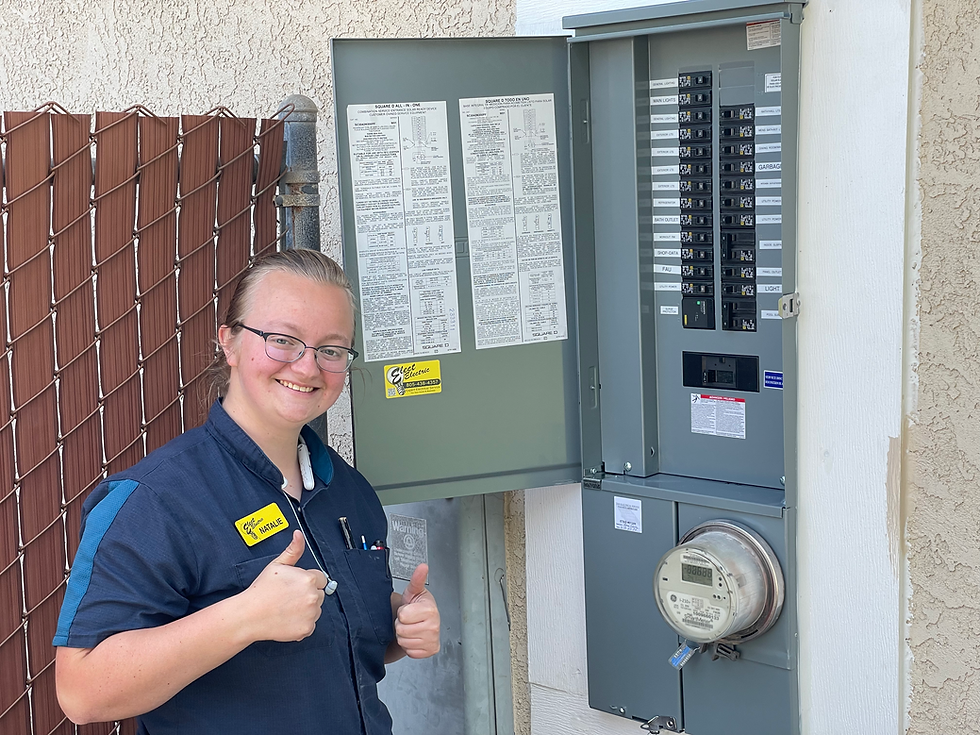 Gray Square D Electrical panel with the door open that you can see the circuit breakers and new cables. Woman smiling with a thumbs up.