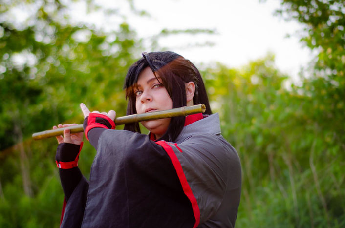 Nancy/Vis wearing a cosplay outfit and playing a flute outside