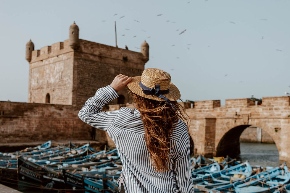 A woman in a straw hat gazes at boats in the harbor.