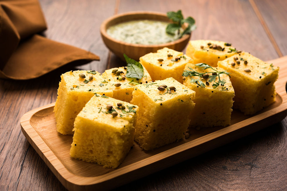 A close-up image of a dokhla, a traditional Gujarati dessert. The dokhla is a golden brown, round cake made with semolina, sugar, and spices. It is topped with a layer of nuts and raisins.