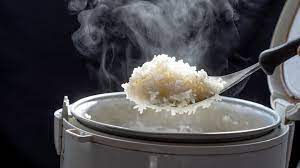 A person pouring rice into a rice cooker.