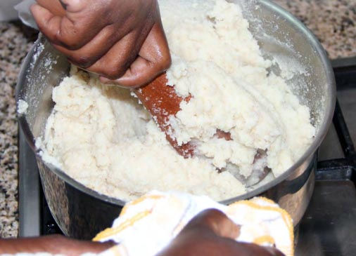 A person stirring Kenyan ugali in a pot.