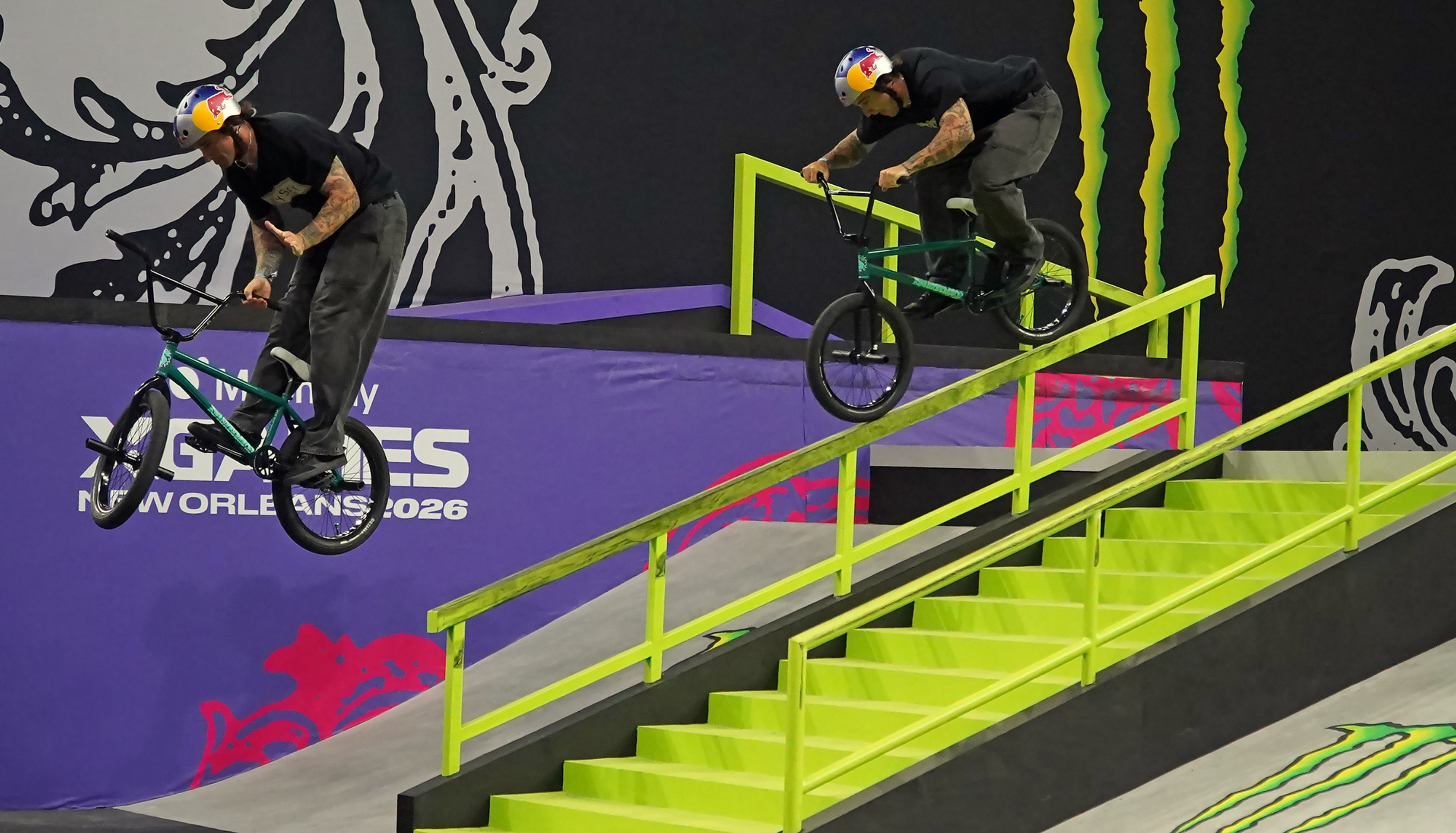 A BMX rider in helmets trick down a neon-green rail inside an indoor park with Monster Energy branding and New Orleans 2026 text.