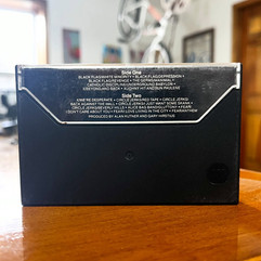 The Decline back of cassette case on a wooden table, with bold title and punk band names.