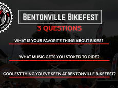FrequentLeigh cover graphic titled "Bentonville BikeFest: 3 Questions," with the FrequentLeigh circular logo (turntable design with tagline "Ride • Listen • Have Fun • Repeat") in the top left. Three questions are listed in white text with red underlines: "What is your favorite thing about bikes?", "What music gets you stoked to ride?", and "Coolest thing you've seen at Bentonville BikeFest?" The background shows a dimmed photo of a BMX rider catching air above dirt jumps with a crowd watching.