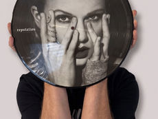 A man holding a record in front of his face