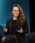 Laurence Paquette delivering a keynote presentation on a dark-lit stage